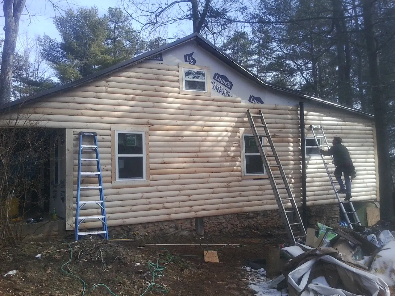 Ladders set against fresh log siding during an exterior remodel in New Paltz