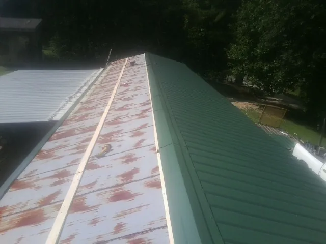 Old rusted panels beside newly installed green metal roofing — Wind Damage Roof Repair by Roofing Brothers in New Paltz