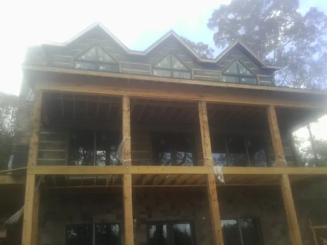 Dormers and porch framing on a large log home under construction — Roof Coating work by our crew in New Paltz
