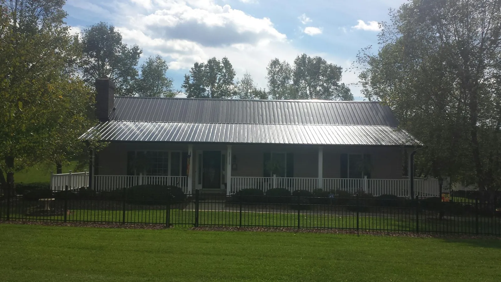 Gray metal roof on a brick ranch with a full width front porch — Gutter Guard Installation work by our crew in New Paltz