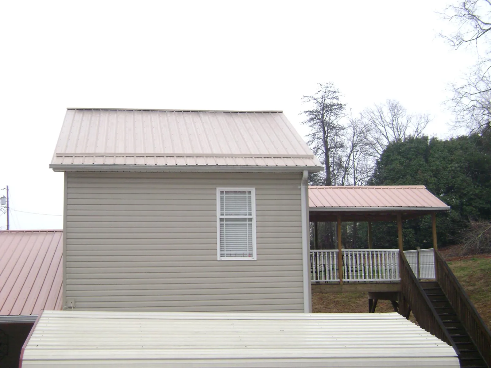Tan metal roofs on a two story addition and attached porch, from a Roof Replacement job in New Paltz