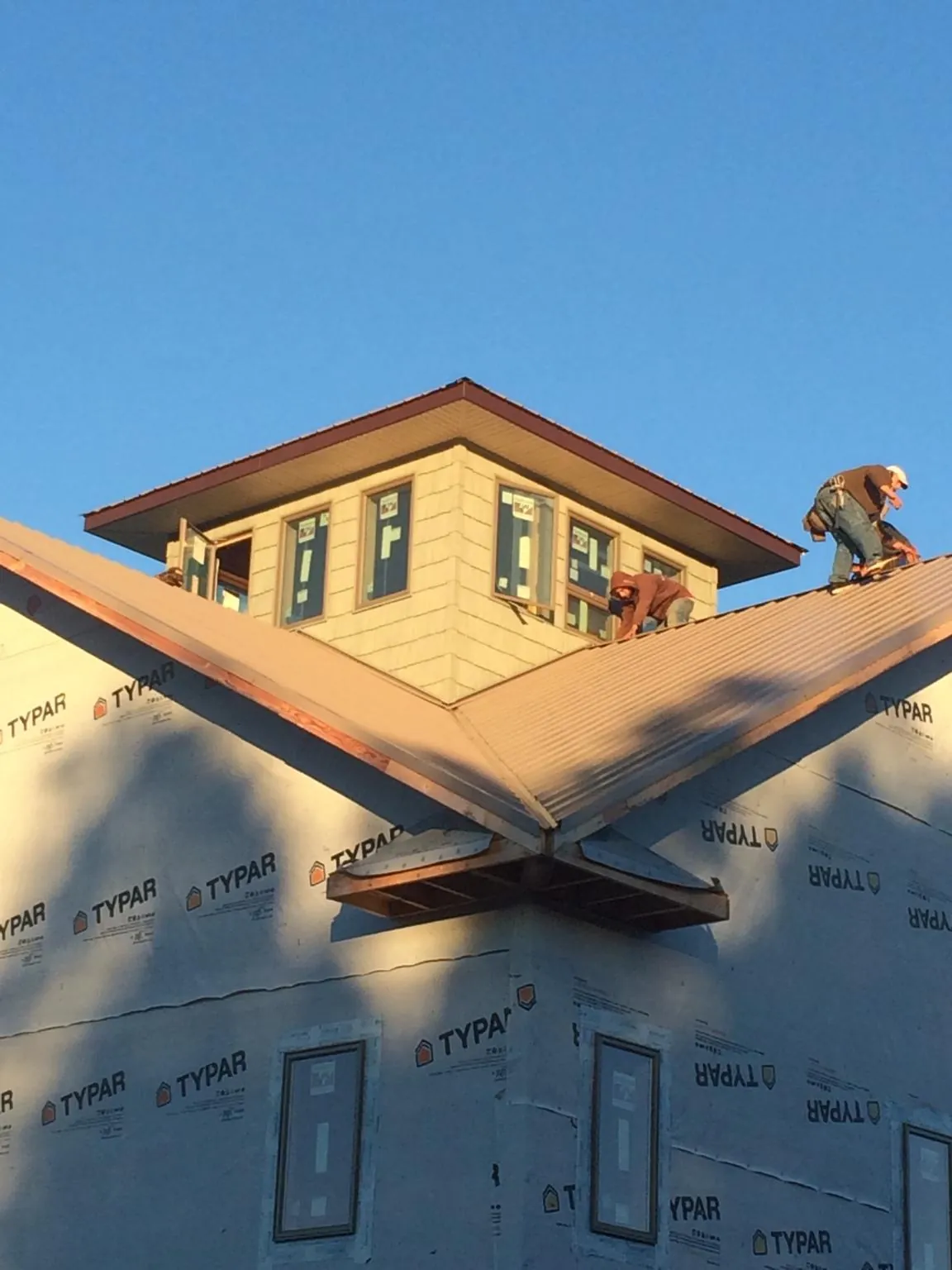 Roofers working around a rooftop cupola on a new metal roof at sunset — Roof Waterproofing in New Paltz by Roofing Brothers